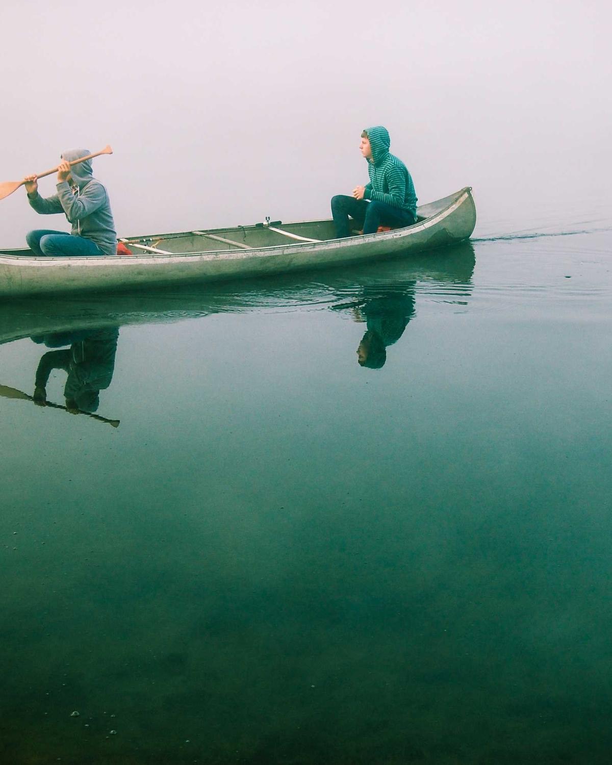Two people in a canoe on a misty lake